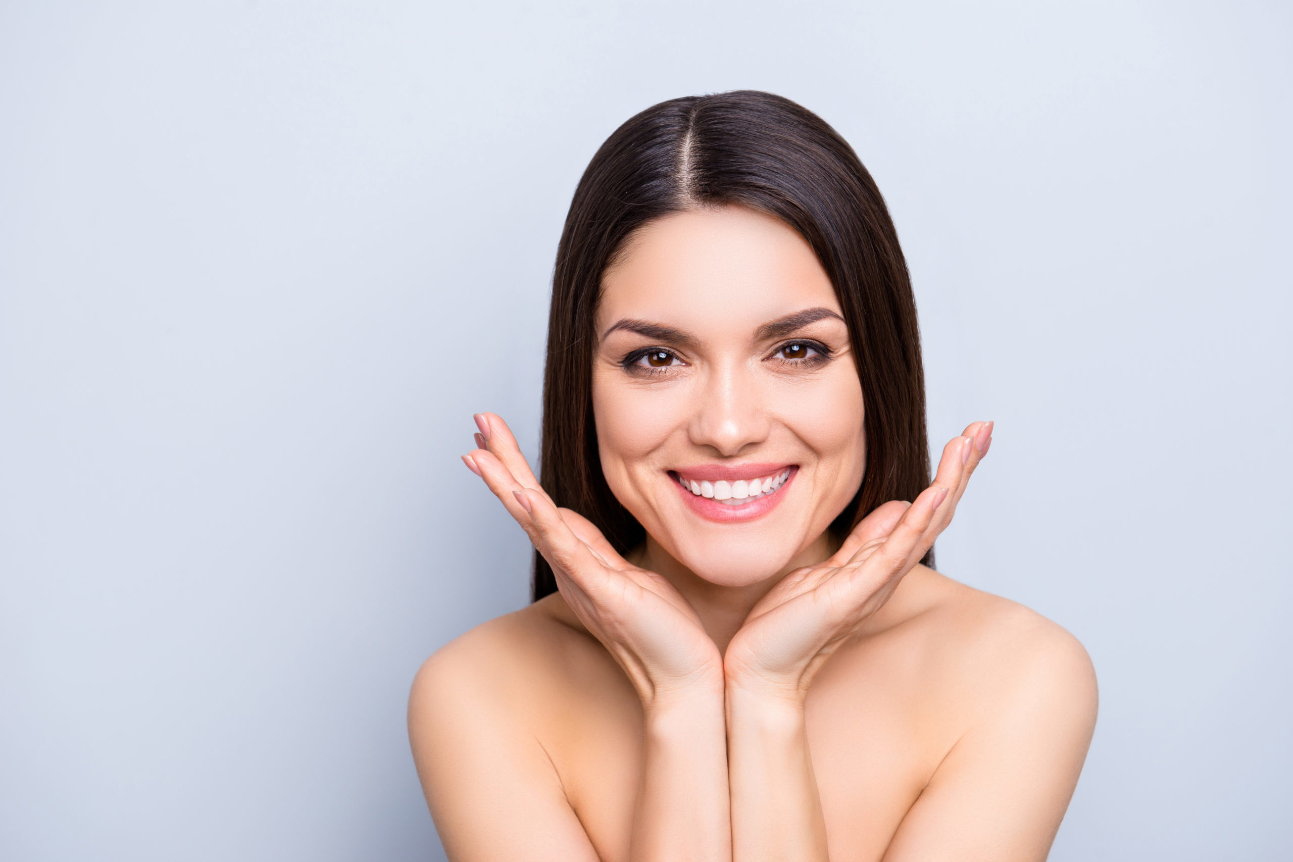 Portrait of gorgeous toothy woman presenting perfect smooth soft idyllic face skin isolated on grey background. Detox botox collagen vitamins minerals wellness wellbeing enhancement concept